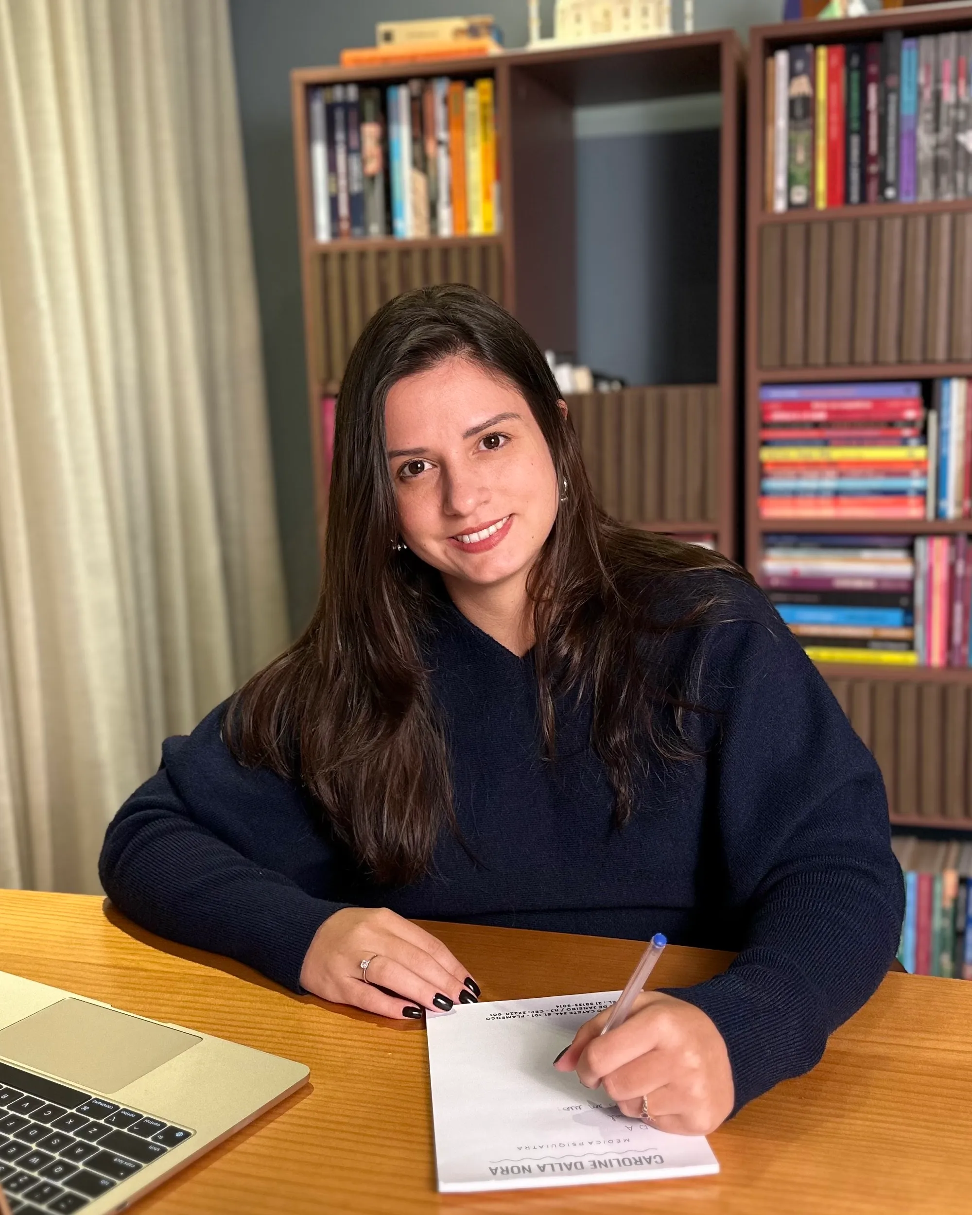 Dra. Caroline Dalla Nora escrevendo à mesa em seu consultório